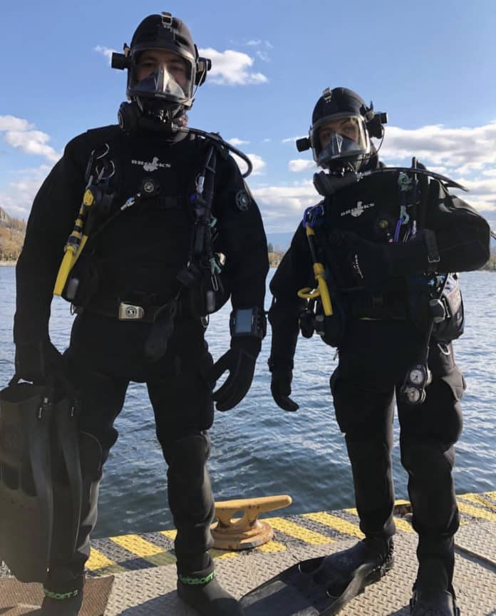 2 commercial divers ready to get into the water wearing full face scuba masks.