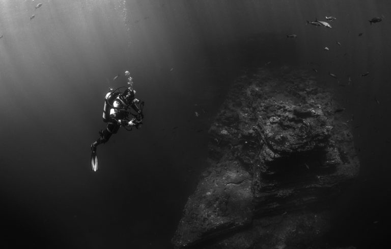 An underwater photographer checking out his equipment during a dive