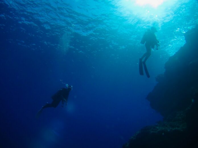 Scuba divers in the blue. We look at the different types of scuba certification levels for beginners, advanced and professional levels.