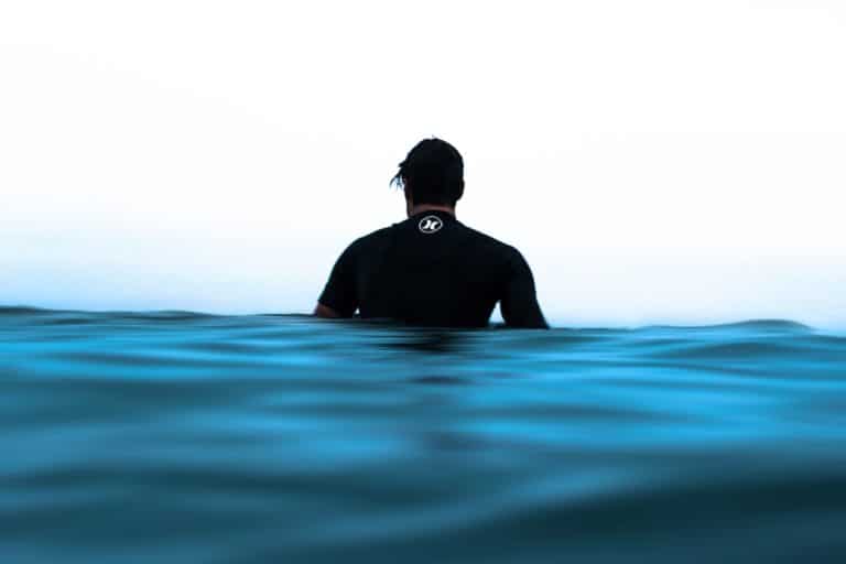 What do men wear under wetsuits? Guy in wetsuit looks out at the ocean.