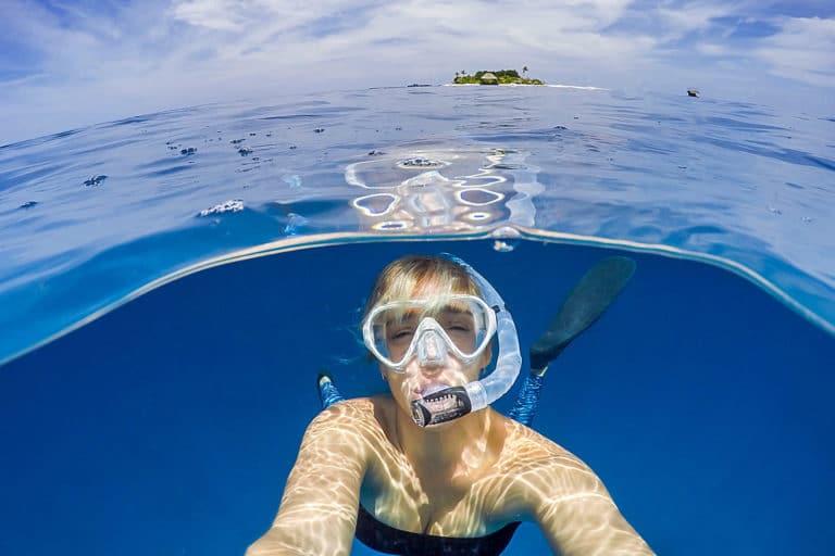 How To Snorkel: Girl snorkeling in front of tropical island.