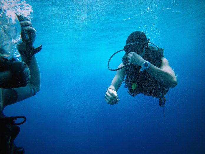 This diver is pinching his nose and using the Toynbee Maneuver to equalize as he descends.