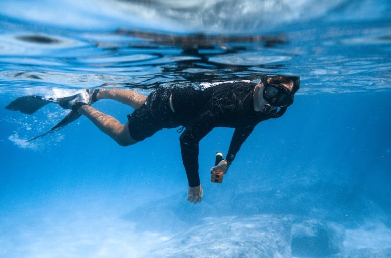 Man snorkeling wearing a rash guard and shorts.